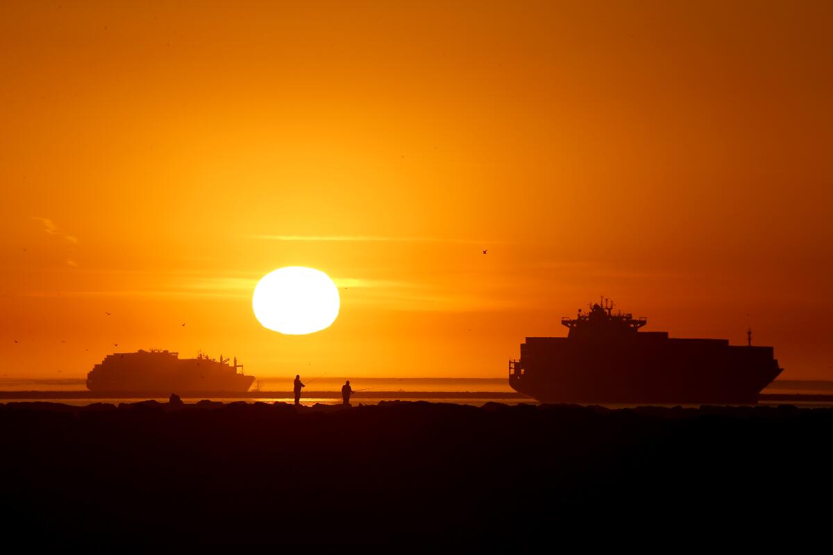 Fishermen set up on the San Gabriel River jetty in front of the setting sun