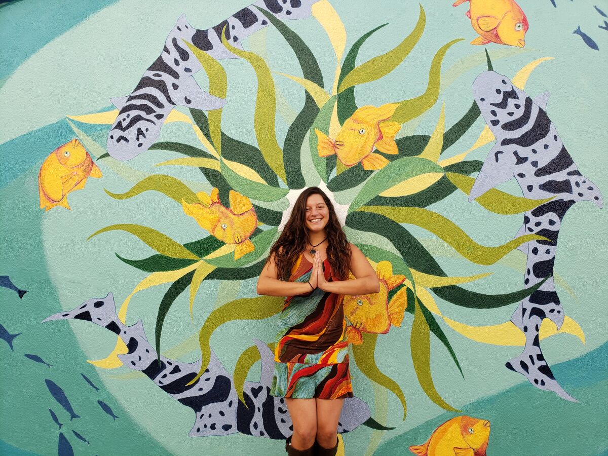 Artist Melanie Atesalp models how her mural in the Arcade Building breezeway could be used for photos. 