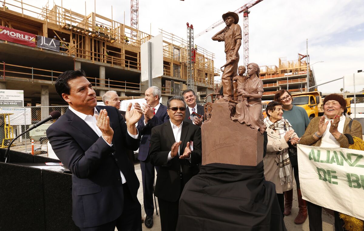 Los Angeles City Councilman Jose Huizar, left, applauds the unveiling of a scale model of a 19-foot monument depicting a Mexican bracero and his family.