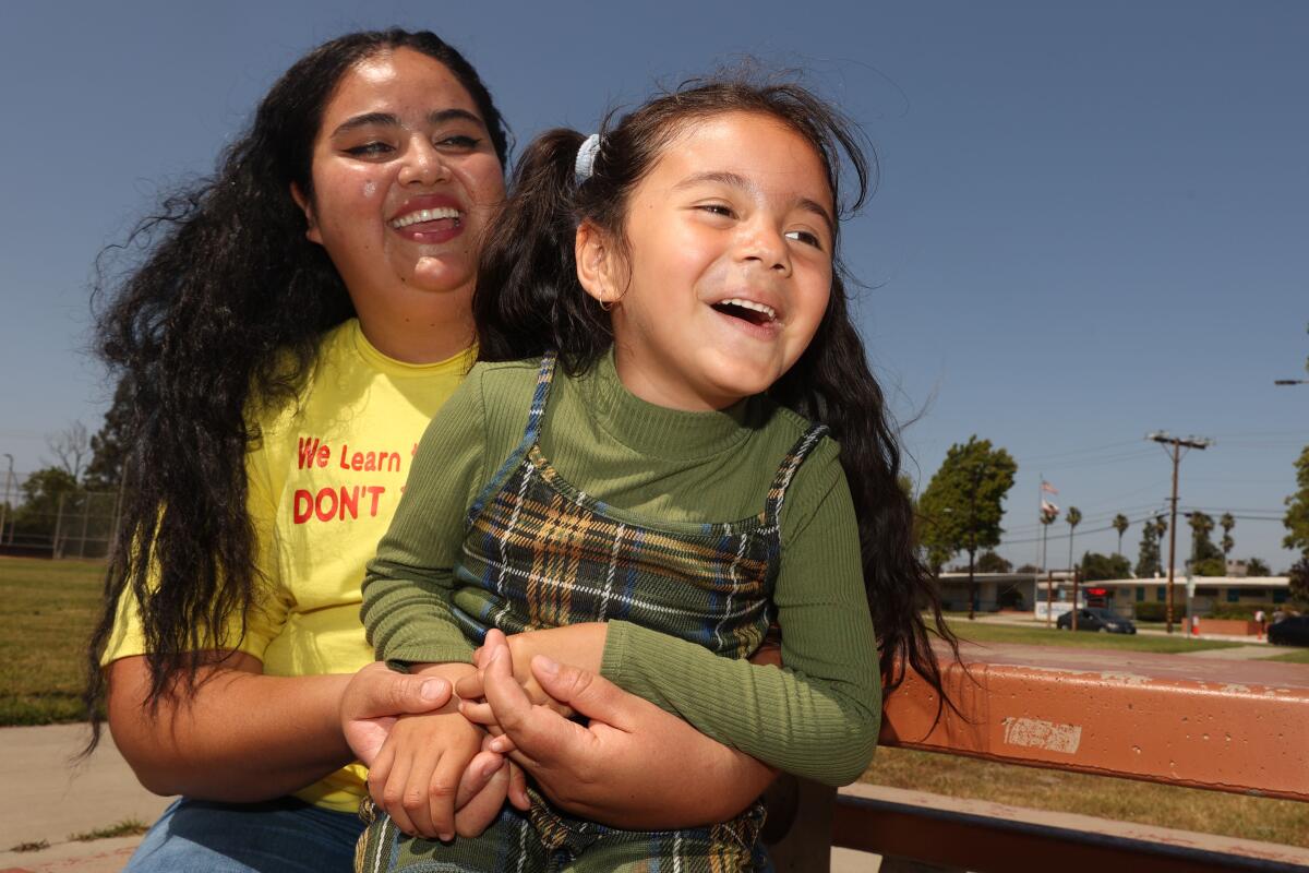 A 4-year-old girl smiles while sitting on her mother's lap at Victoria Community Regional Park in Carson.