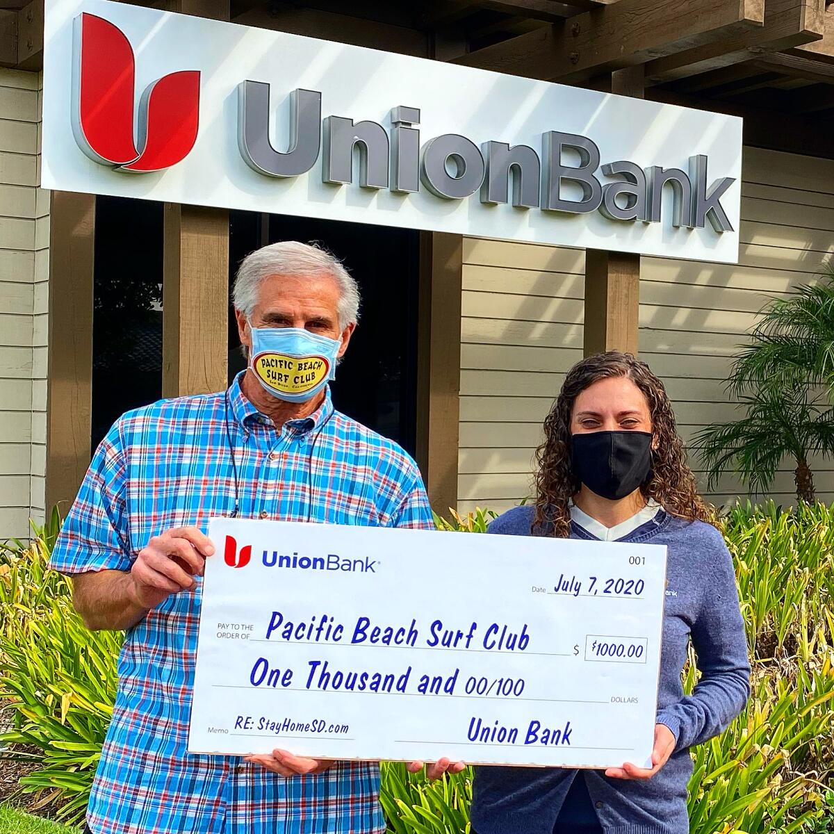 PB Surf Club President Ron Greene accepting a $1,000 donation from Cathy Principato of Union Bank