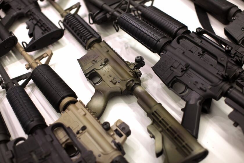 A collection of AR-15-style guns, including the Bushmaster (center, camouflauge coloring), were on display as Los Angeles city officials announced that more than 2,000 firearms were collected during the Dec. 26 gun buyback program.