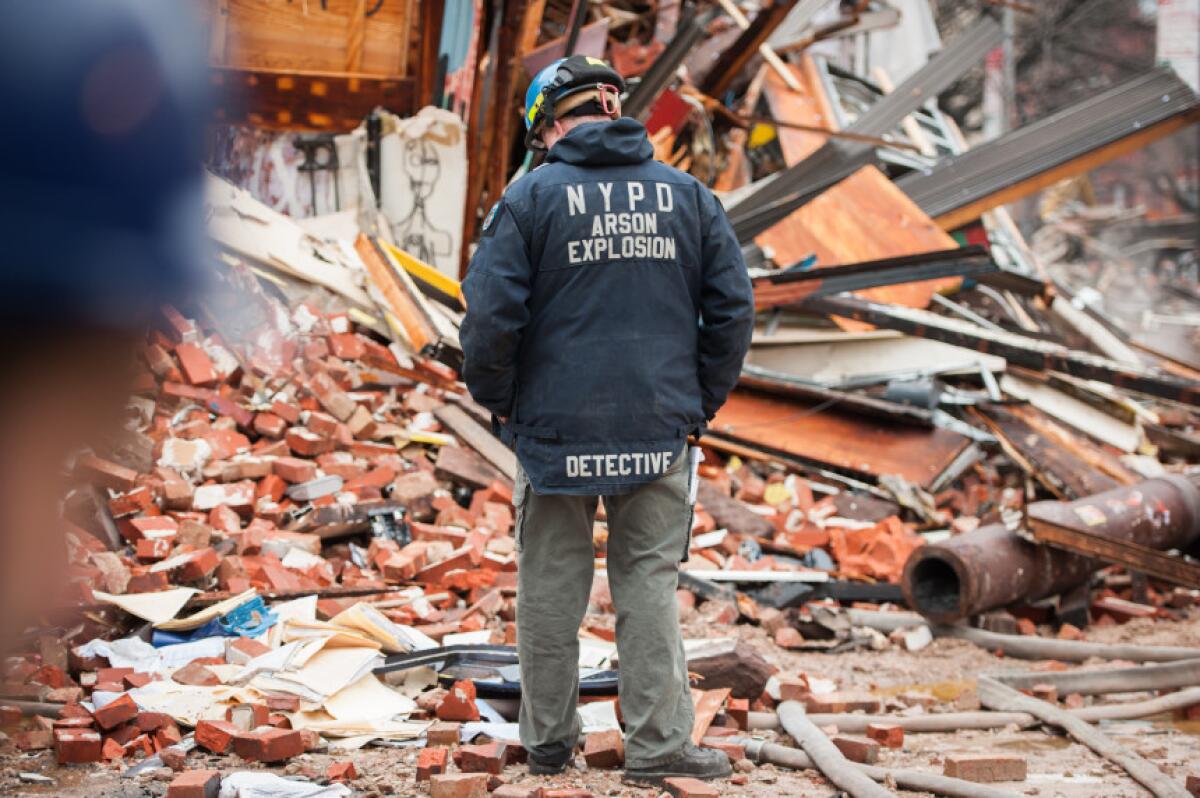 Un agente de policía examina los restos de un edificio derrumbado tras una explosión e incendio en Manhattan, en Nueva York, el viernes 27 de marzo del 2015.
