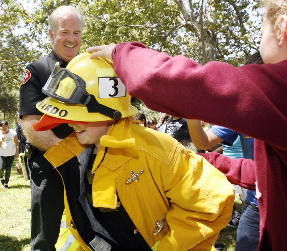 With the help of Glendale Fire Battalion Chief Tom Propst, Aedan Molina, 11, takes off for the final leg of a turnout race for the Junior Fire Program by the Glendale Fire Department at Verdugo Park.