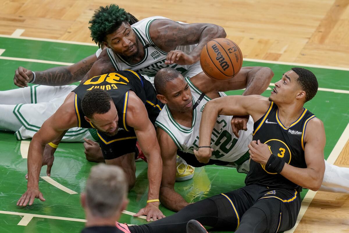 Boston Celtics center Al Horford (42) and guard Marcus Smart, top, battle for a loose ball against Golden State Warriors guard Jordan Poole (3) and guard Stephen Curry (30) during the fourth quarter of Game 3 of basketball's NBA Finals, Wednesday, June 8, 2022, in Boston. (AP Photo/Steven Senne)