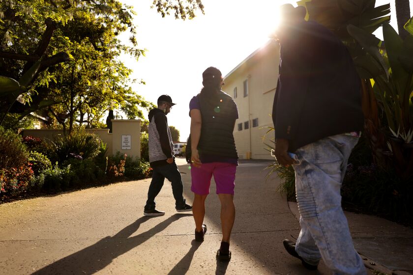 Mary Liciaga, center, and her friend Jeremiah Boseman, right, escort Anthony Mazzucca, 30, at left, back to Meadowbrook Behavioral Health Center where he currently resides, on Tuesday, April 5, 2022. (Christina House / Los Angeles Times)