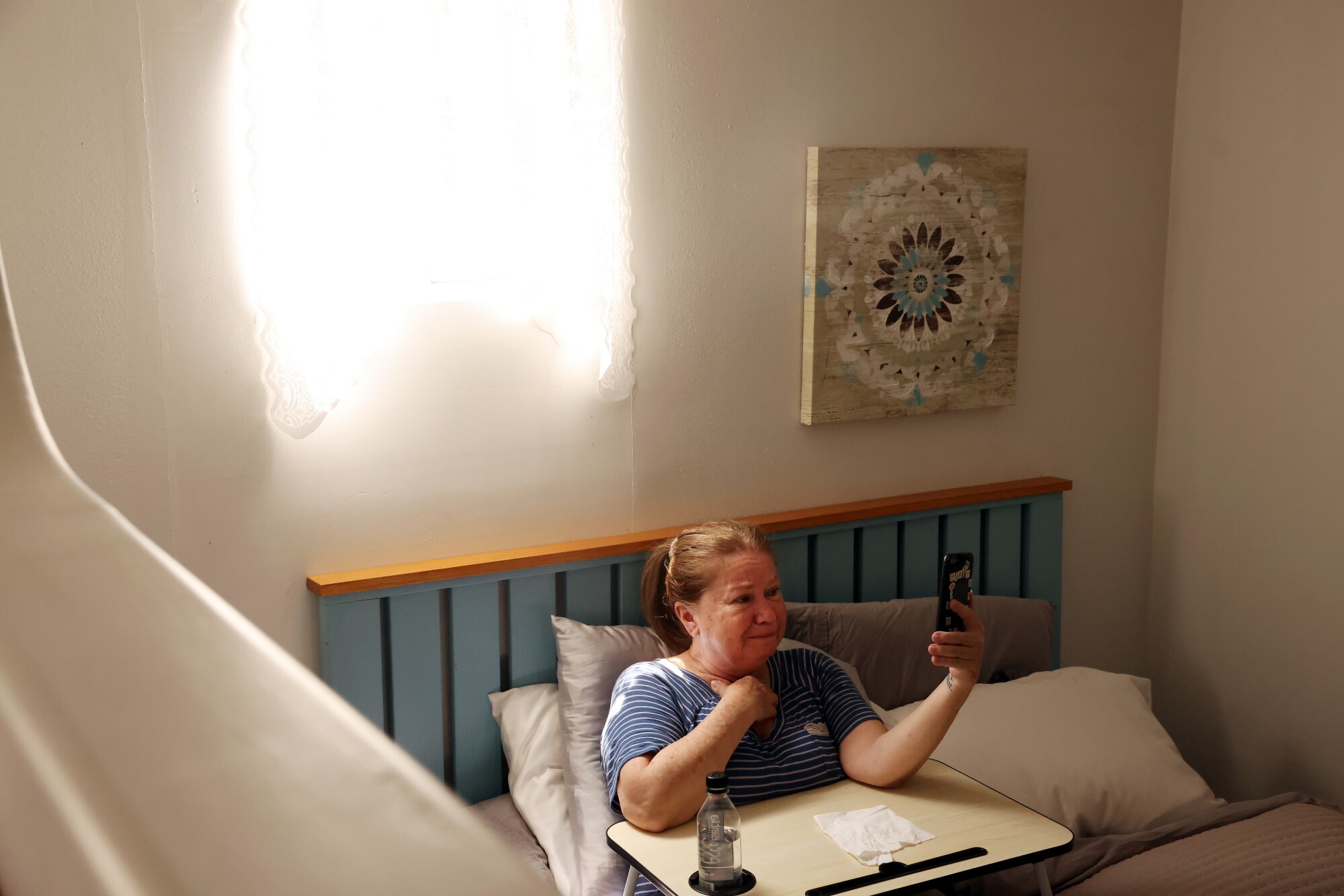 A woman on a bed FaceTimes on a phone
