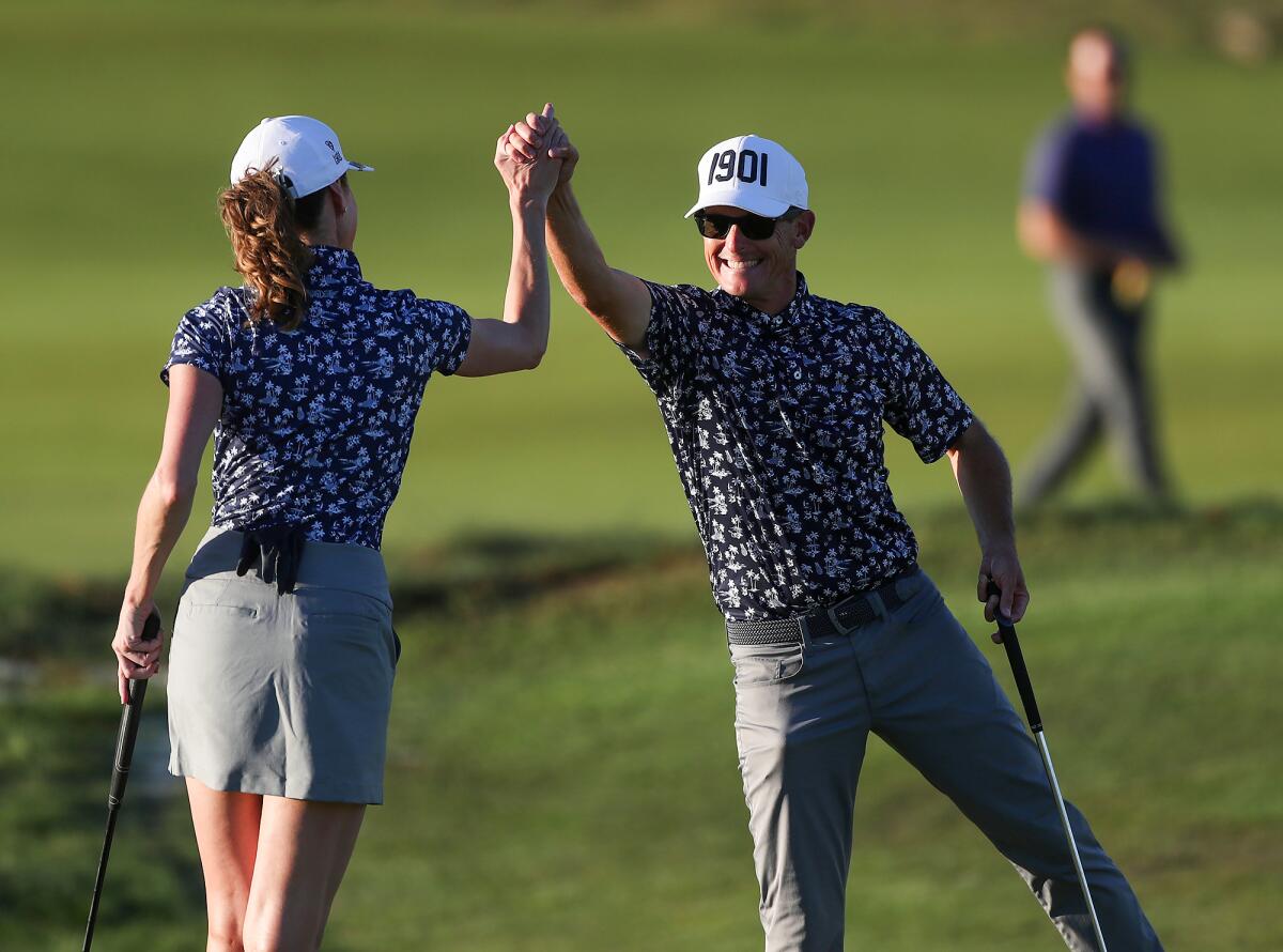 Geoff Cochrane gives teammate Diane Booth a high-five after she sank a long putt during last year's Jones Cup.