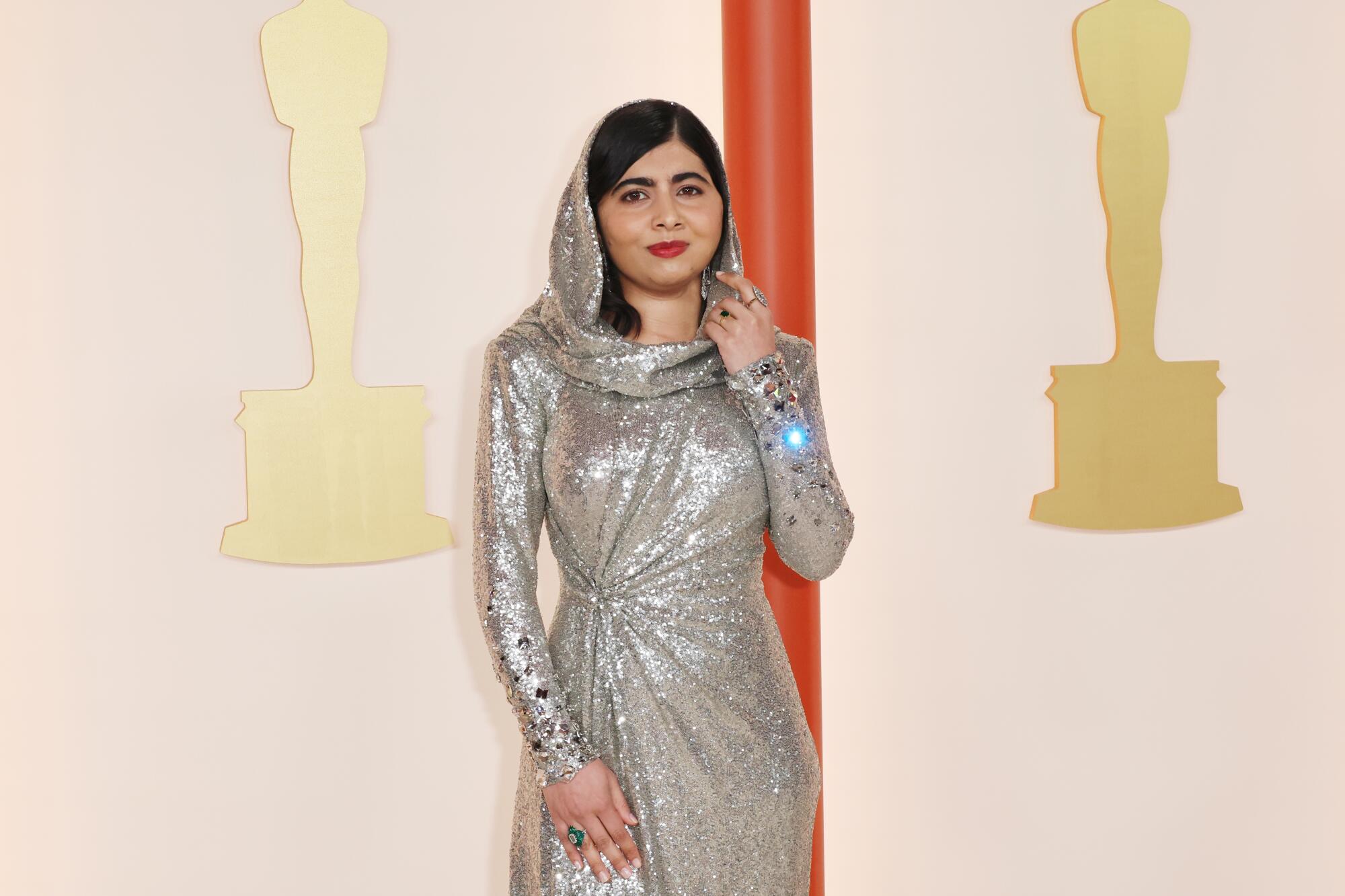 Malala Yousafzai in a silvery gown and head scarf.