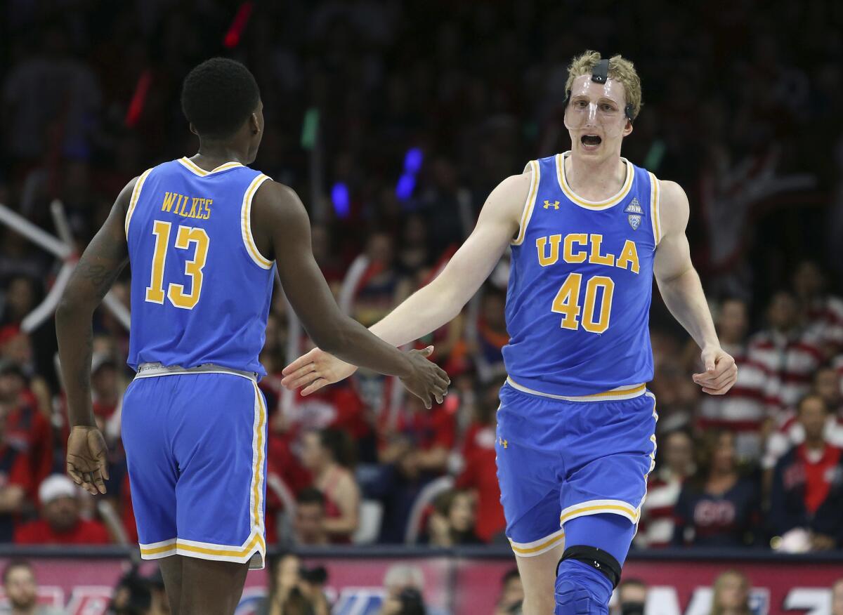 UCLA's Thomas Welsh reacts with teammate Kris Wilkes after a dunk against Arizona on Feb. 8.