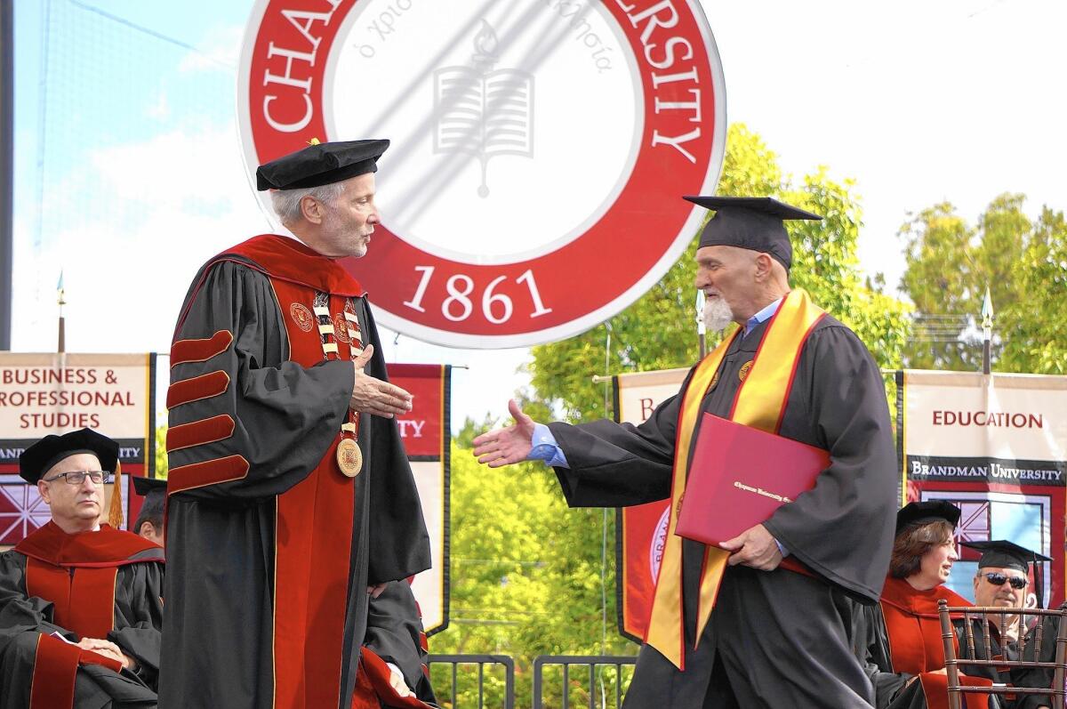 Joe Blackburn walks across the stage at Brandman University's 2016 commencement ceremony to shake Chancellor Gary Brahm's hand.