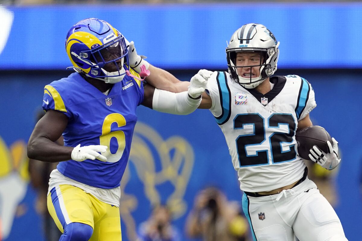 Former Panthers running back Christian McCaffrey (22) stiff-arms Rams cornerback Derion Kendrick.