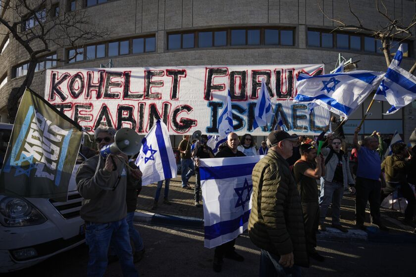 Demonstrators wave flags during a protest against plans by Prime Minister Benjamin Netanyahu's new government to overhaul the judicial system, outside the offices of the conservative Kohelet Policy Forum think tank, which is helping spearheaded the overhaul to Israel's judiciary, in Jerusalem, Thursday, March 9, 2023. (AP Photo/Ohad Zwigenberg)