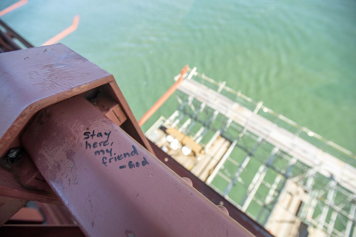 A note reads, "Stay here, my friend" on a handrail on the Golden Gate Bridge