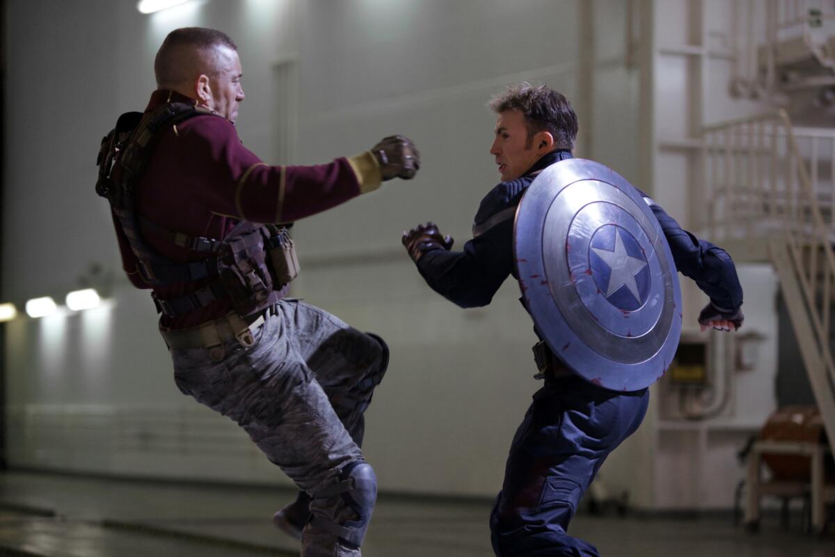 This image released by Marvel shows George St-Pierre, left, and Chris Evans in a scene from "Captain America: The Winter Soldier."