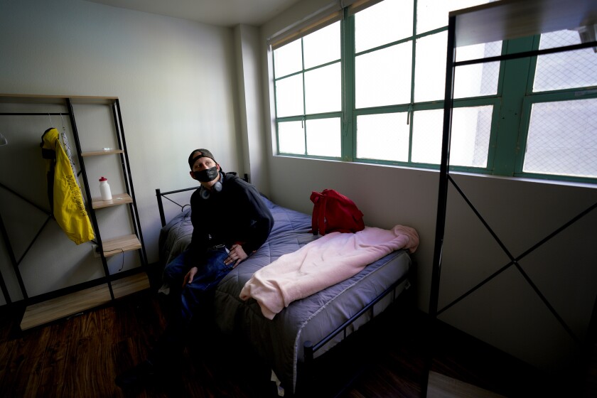 Robert Plummer sits on the bed in his room at Urban Street Angel in downtown San Diego.