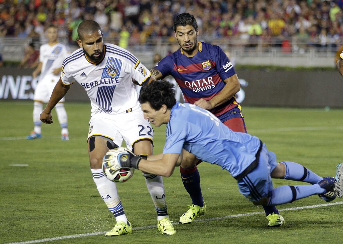 Los Angeles Galaxy goalkeeper Brian Rowe, front, makes a save in front of Galaxy's Leonardo, left, and FC Barcelona's Luis Suarez during the first half of an International Champions Cup soccer match on Tuesday at the Rose Bowl.