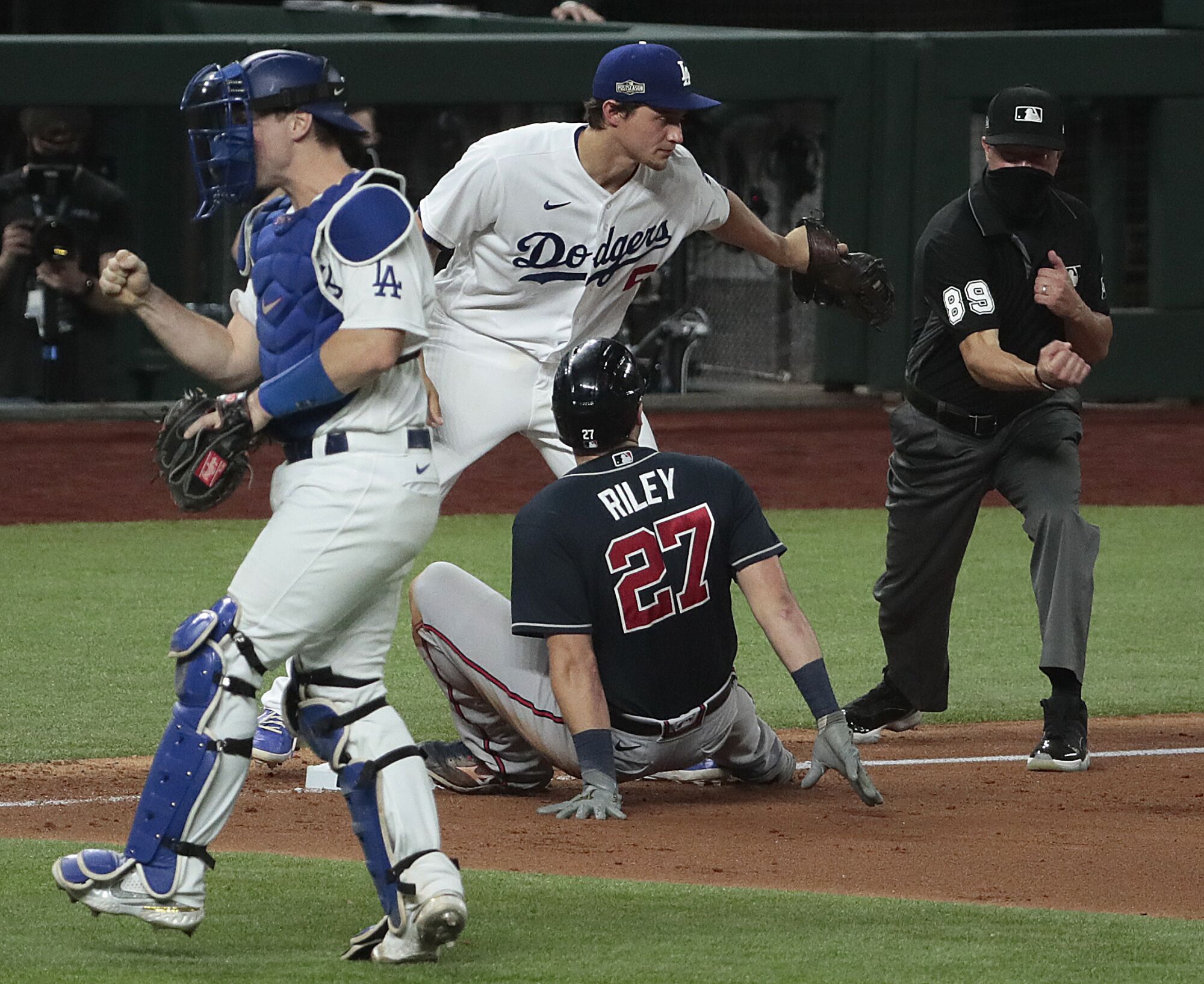 Catcher Will Smith celebrates as the ump calls Austin Riley out after a tag by Corey Seager at third.