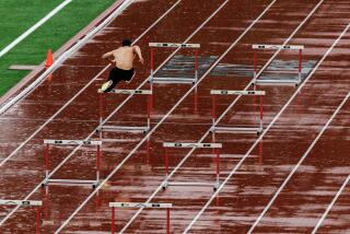 RIVERSIDE, CA - FEBRUARY 20, 2024: A shirtless member of the track team practices the hurdles in the pouring rain on a wet track at Riverside City College on February 20, 2024 in Riverside, California.(Gina Ferazzi / Los Angeles Times)