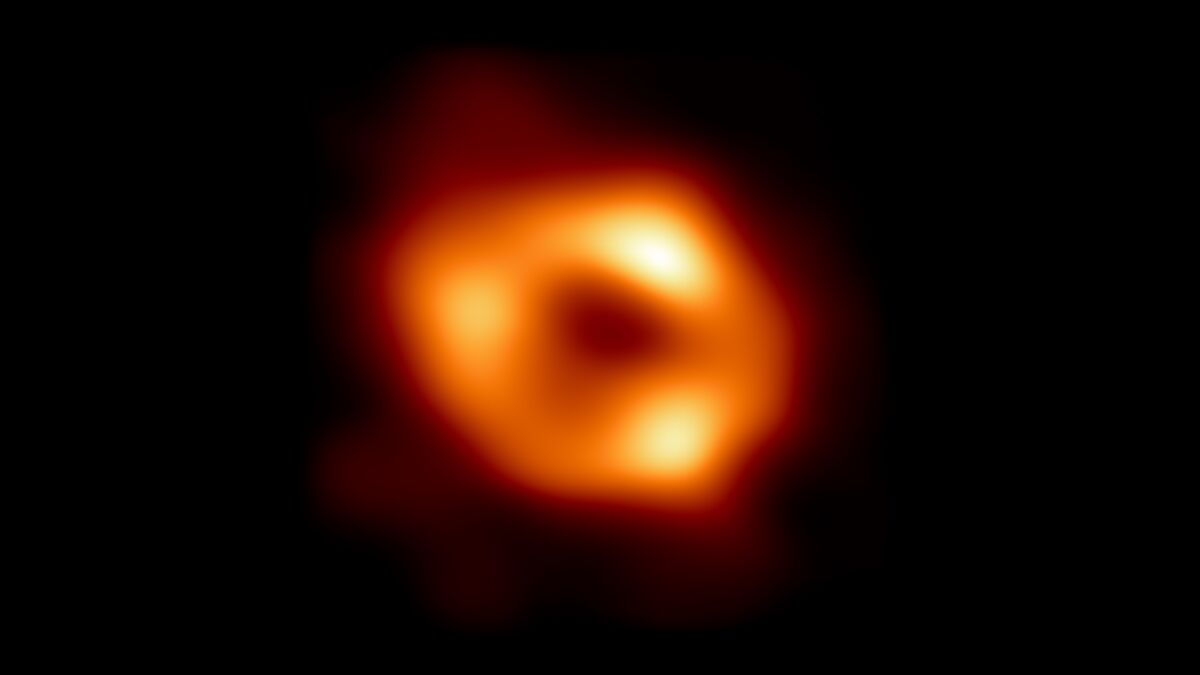 A fuzzy bright orange doughnut-shaped object glows against a black background