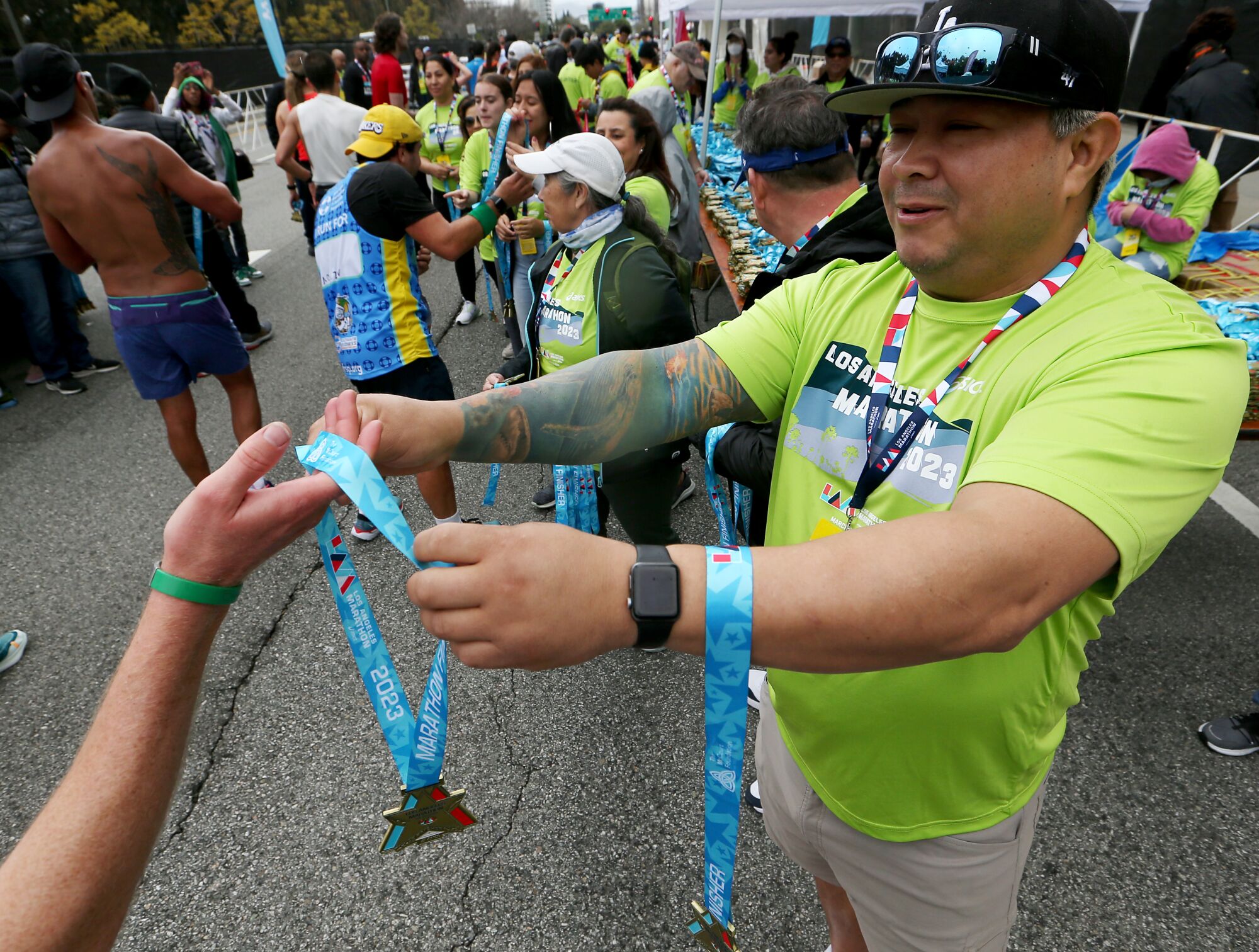 Volunteers hold out award medals to runners for finishing in the Los Angeles Marathon.
