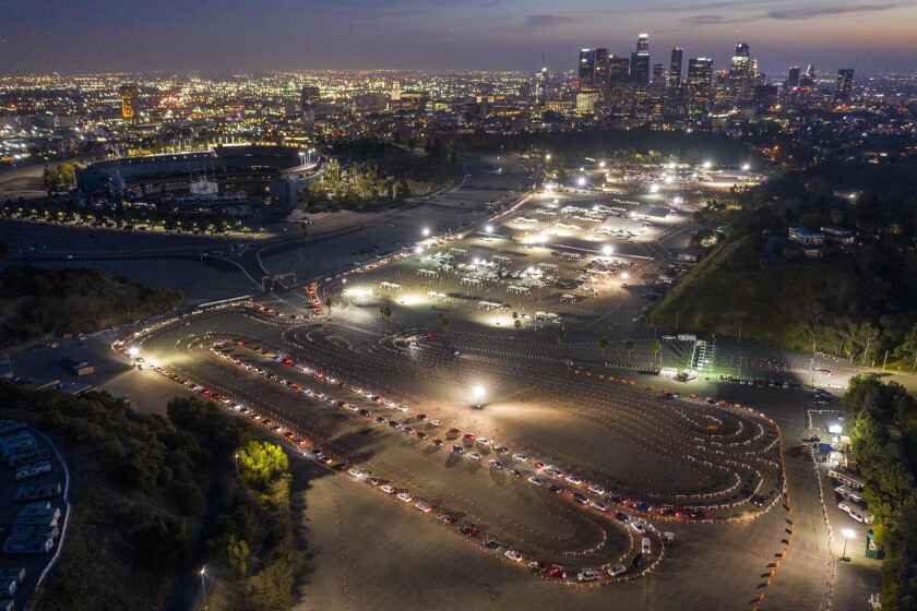 An aerial nighttime view of lines of cars winding around the Dodger Stadium parking lot.