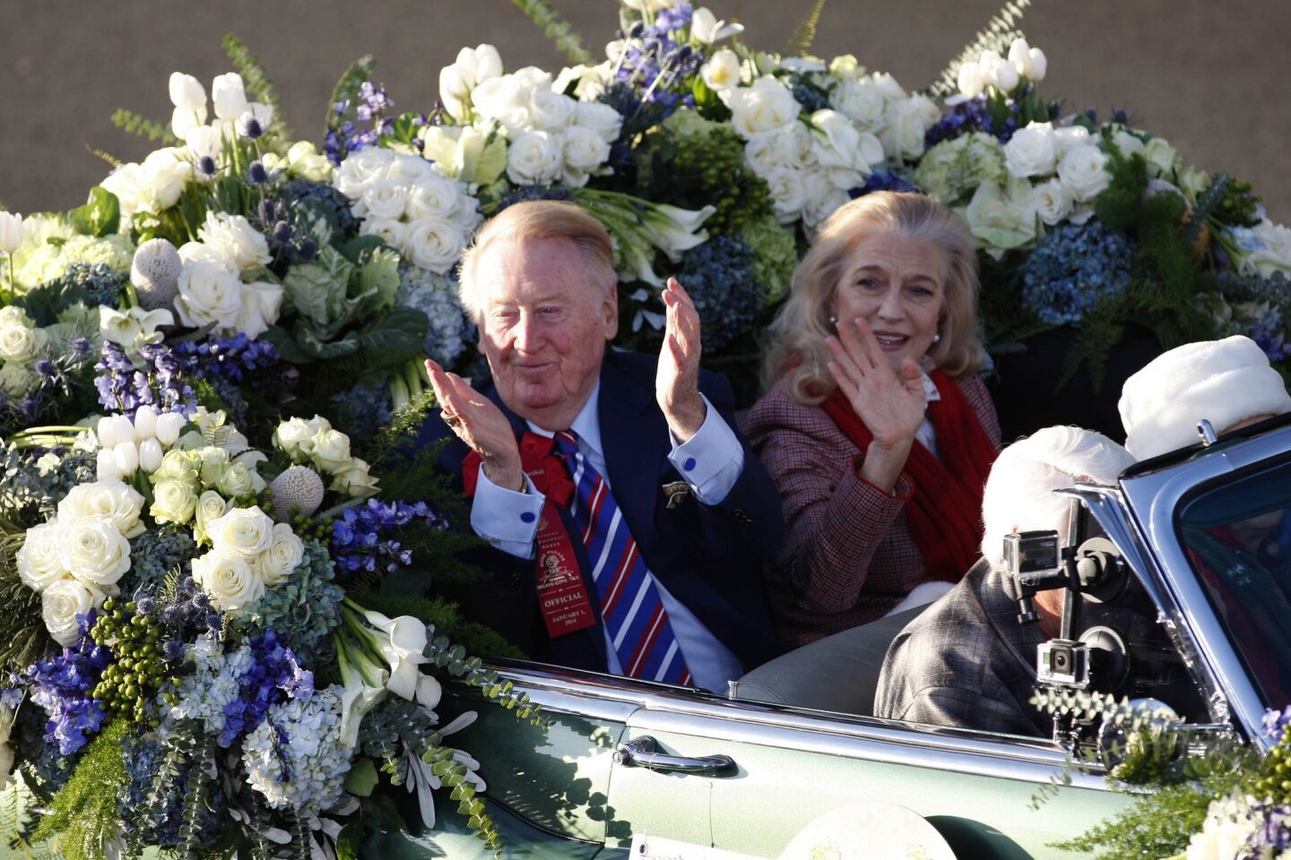 Vin Scully waves to fans as he rides in a car with his wife, Sandra Hunt, while serving as the 2014 Rose Parade Grand Marshal.