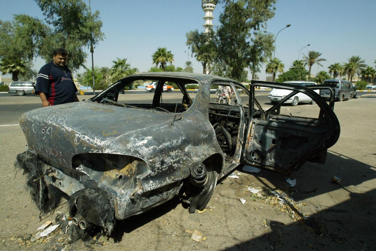 An Iraqi looks at a burned car at the site where Blackwater guards who were escorting U.S. Embassy officials opened fire a week before in Baghdad in 2007.