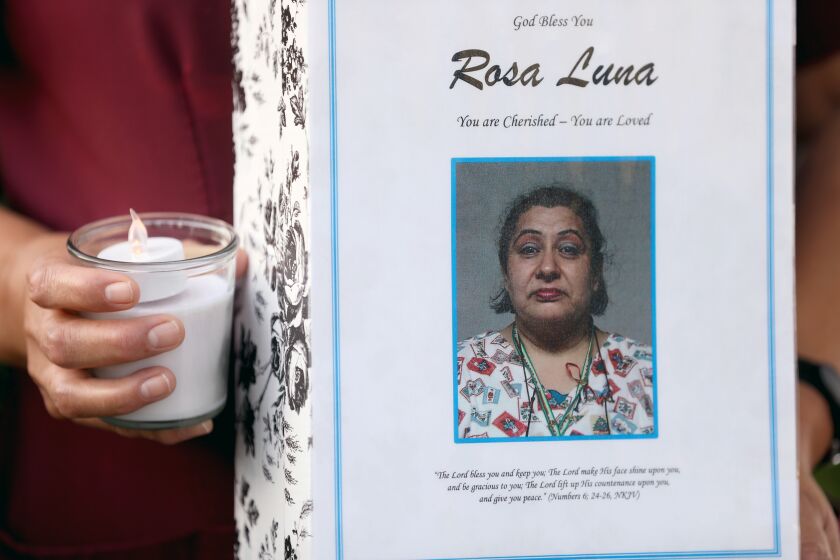RIVERSIDE, CA -- MAY 15: Lorena Jimenez, an environmental services employee at Riverside Community Hospital, along with co-workers, family and friends hold a candlelight vigil for Rosa Luna, 68, at Riverside Community Hospital, on Friday, May 15, 2020, in Riverside, CA. Jimenez is holding a photo of Luna. Rosa, an Environmental Services Housekeeper for 25 years at Riverside Community Hospital, died May 4, 2020 from COVID-19. She is survived by her daughter and two grandchildren. (Gary Coronado / Los Angeles Times)