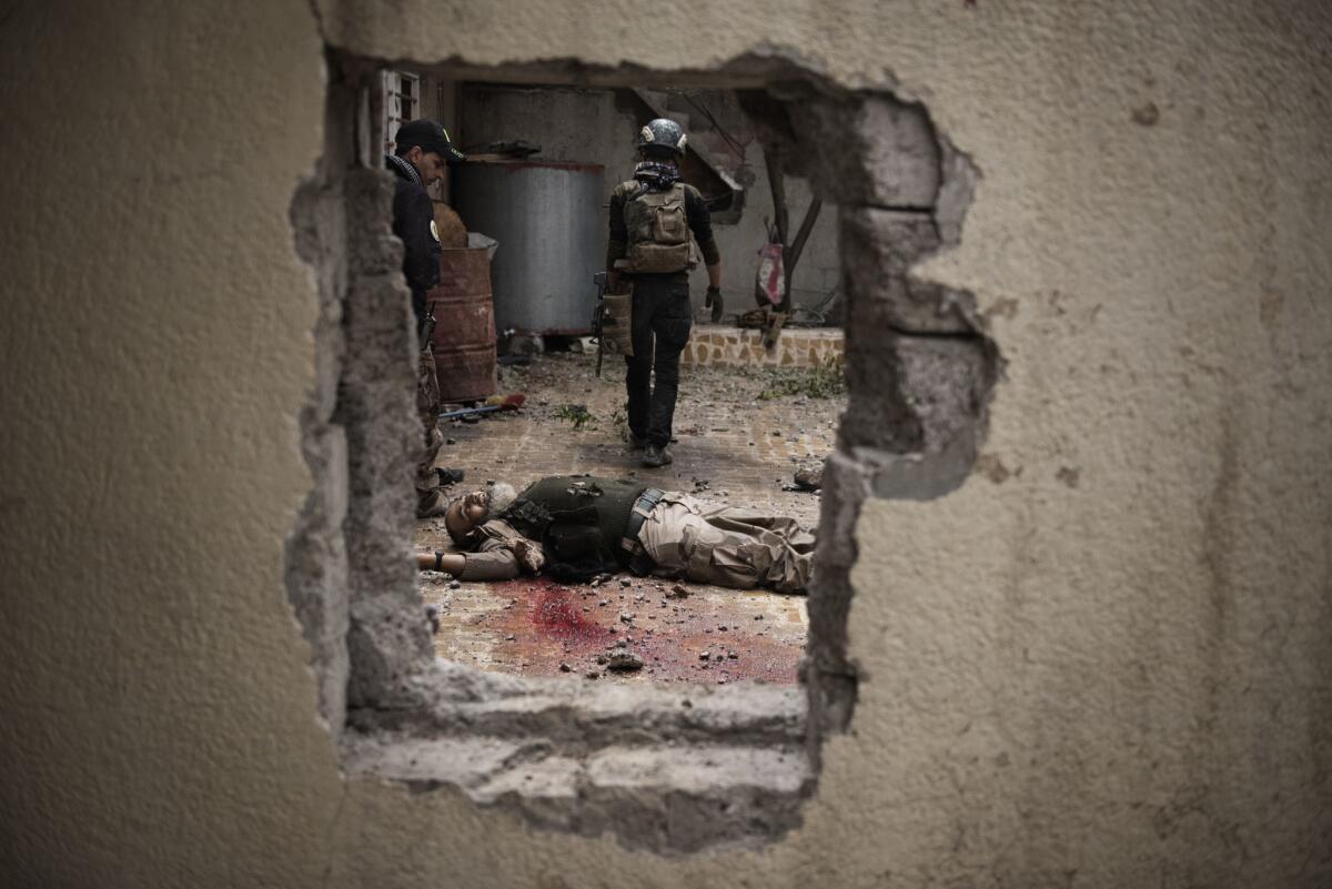 Soldiers walk past an Islamic State fighter killed during a house to house advance in west Mosul, Iraq.