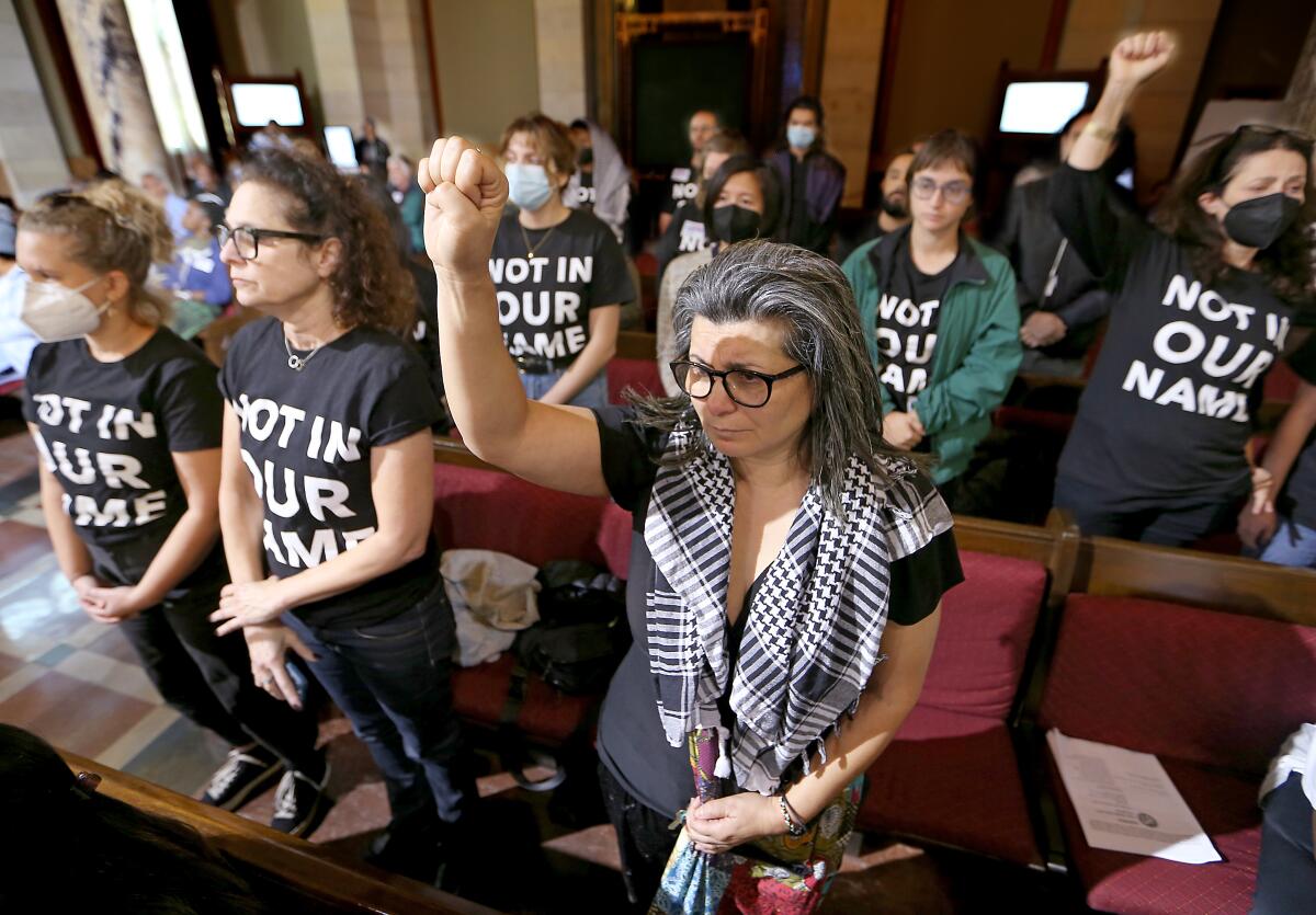Activists stand in rows wearing "Not In Our Name" shirts.
