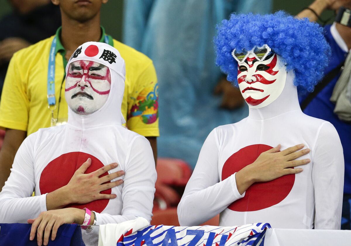 Japanese fans listen to their nation's national anthem before a World Cup soccer match between Ivory Coast and Japan on June 14 at the Arena Pernambuco in Recife, Brazil.