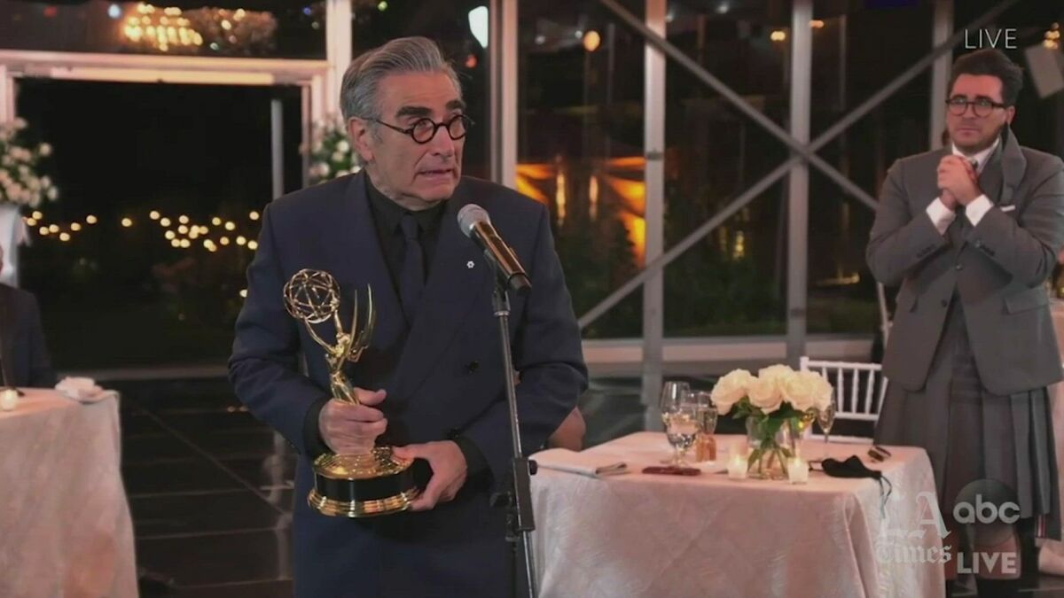 Eugene Levy accepts his Emmy while his son, Daniel, watches.