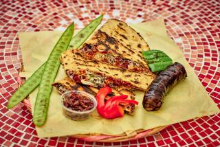 LOS ANGELES, CA - SEPTEMBER 22: A tlayuda filled with chorizo, with a side of blood sausage seasoned with mint grown in the garden, at Poncho's Tlayudas on Friday, September 22, 2023 in Los Angeles, CA. (Shelby Moore / For The Times)