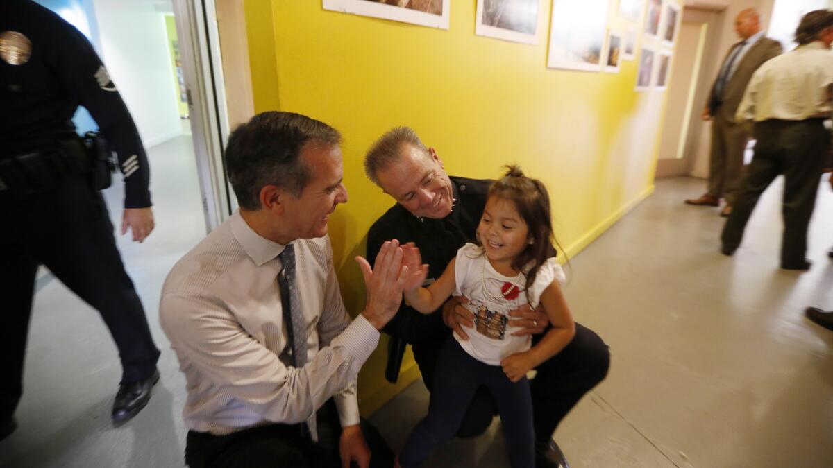 Mayor Eric Garcetti and his choice for police chief, LAPD veteran Michel Moore, stop to greet Tiffany Villa, 3, at El Centro del Pueblo in Echo Park.