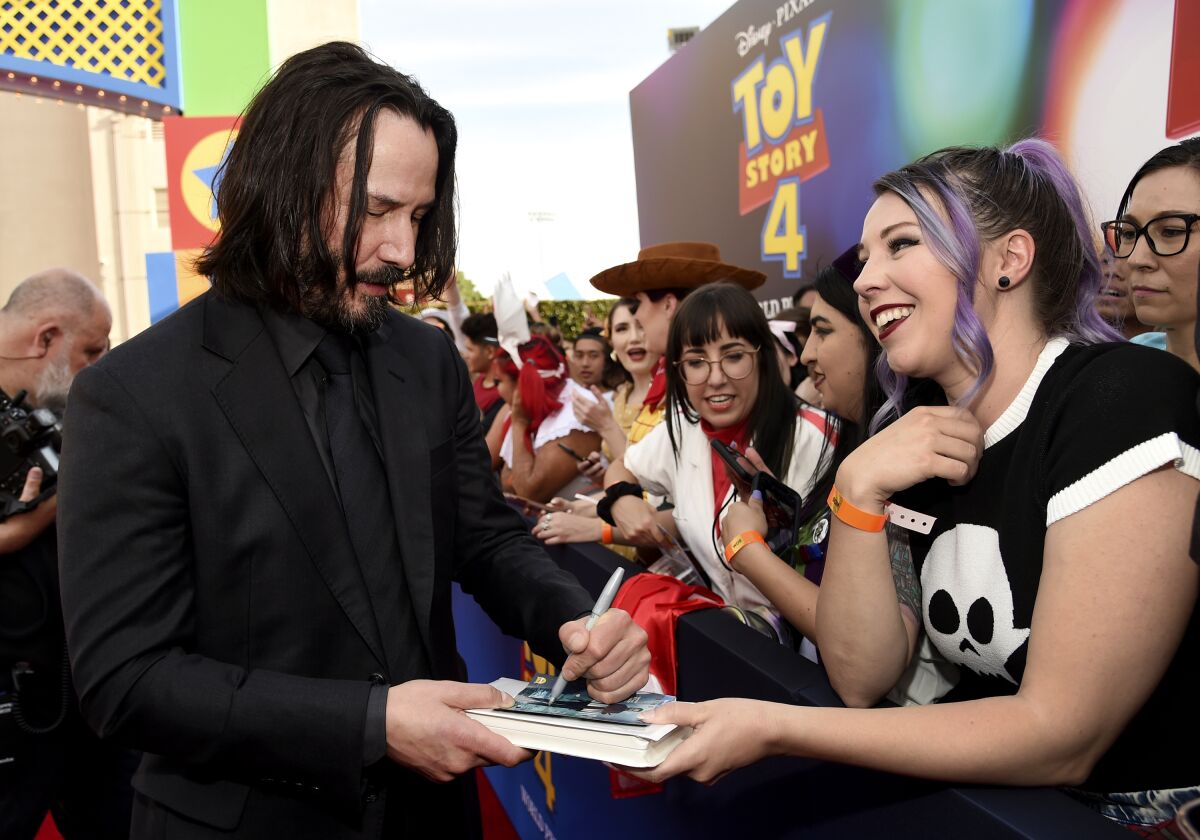 A man in a black suit signs an autograph for a fan.
