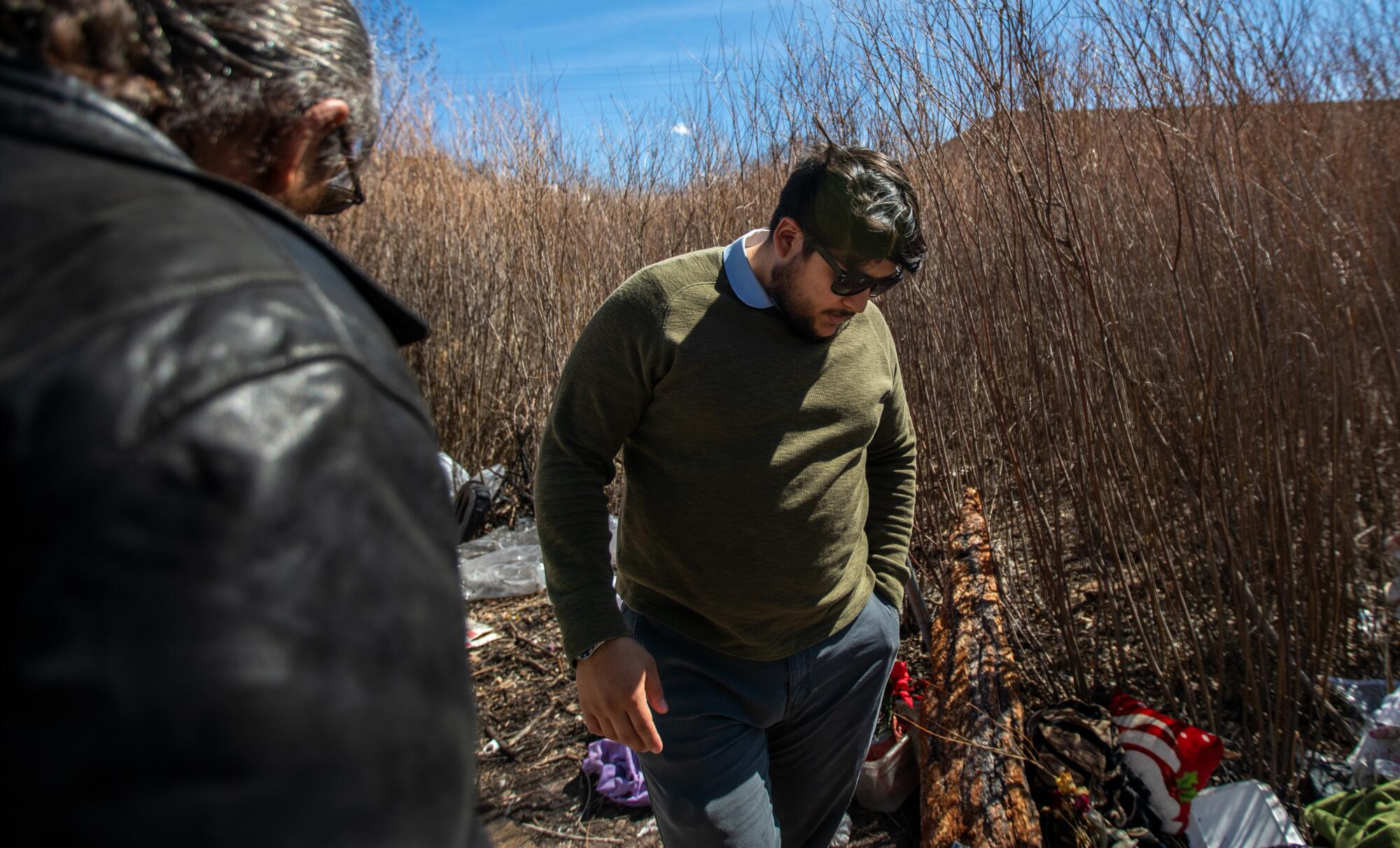 Two men stand in a litter-strewn area outdoors 