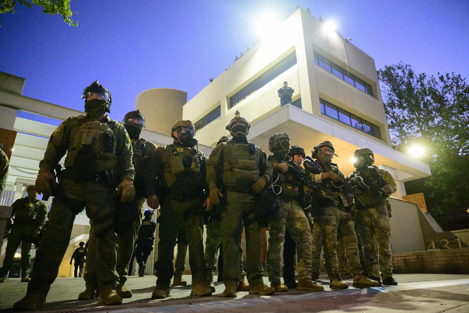 Federal agents, including members of the Department of Homeland Security, Border Patrol, and others, stand guard outside an Immigration and Customs Enforcement (ICE) facility in downtown Portland, Oregon, on October 6, 2025. President Donald Trump threatened on October 6, 2025, to use emergency powers against rebellion to deploy more troops into Democratic-led US cities, intensifying his rhetoric as his attempts to mobilize the military face legal challenges. Trump openly mulled use of the Insurrection Act after a federal judge in Oregon temporarily halted a National Guard deployment in Portland, while another judge in Illinois allowed a similar move to proceed for now in Chicago. (Photo by Mathieu Lewis-Rolland / AFP) (Photo by MATHIEU LEWIS-ROLLAND/AFP via Getty Images)