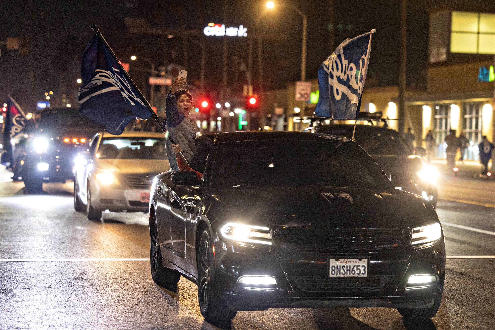 Cars sporting large Dodgers flags drive down Whittier Boulevard to celebrate the team's World Series win.