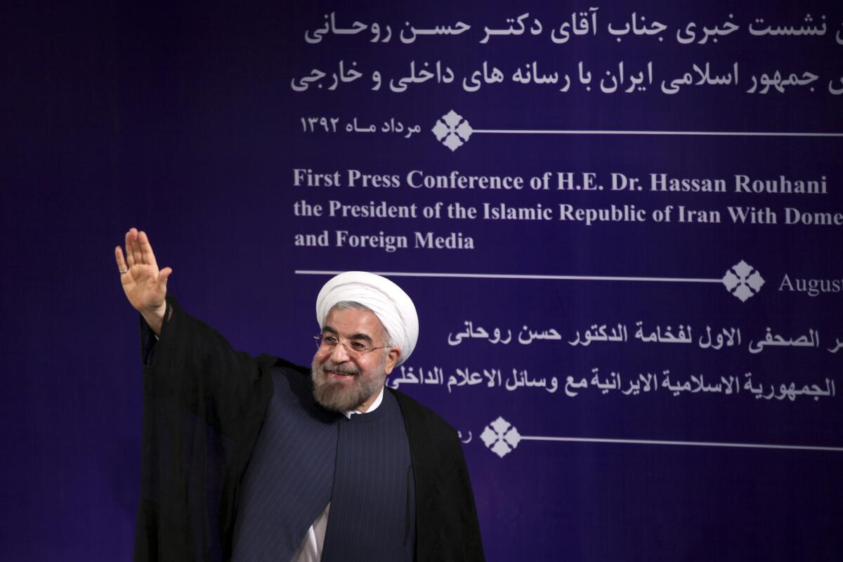 Iran's new president, Hassan Rouhani, waves to reporters at the conclusion of a news conference in Tehran.