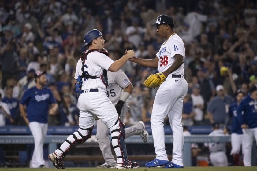 Los Angeles Dodgers relief pitcher Yency Almonte (38), and catcher Will Smith (16) celebrate the team's 5-3 win over the Colorado Rockies in a baseball game in Los Angeles, Monday, July 4, 2022. (AP Photo/Kyusung Gong)