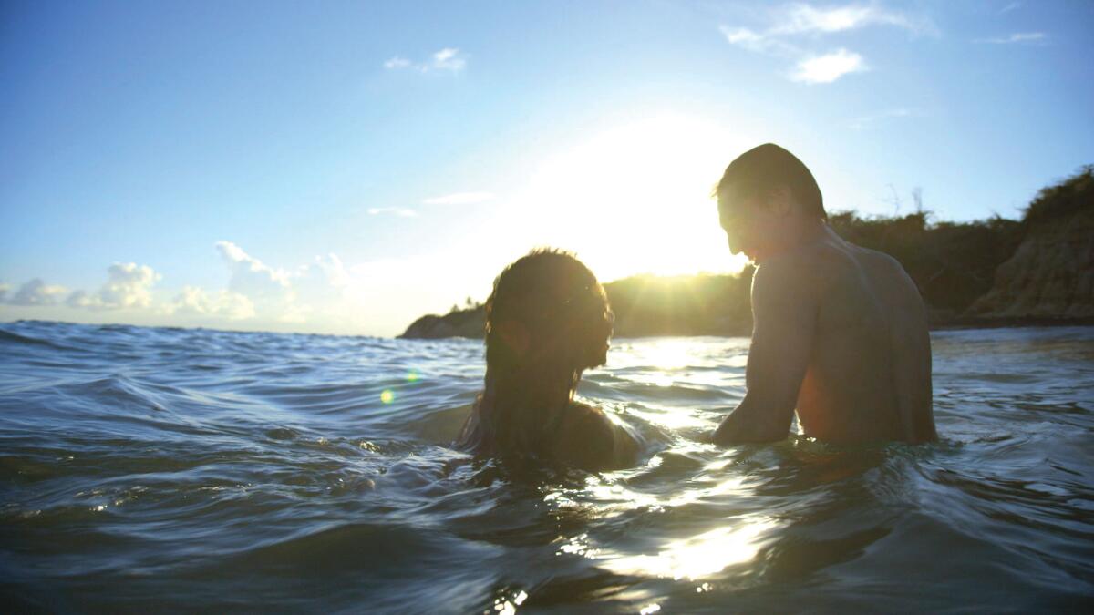 A man and a woman swim in the ocean.