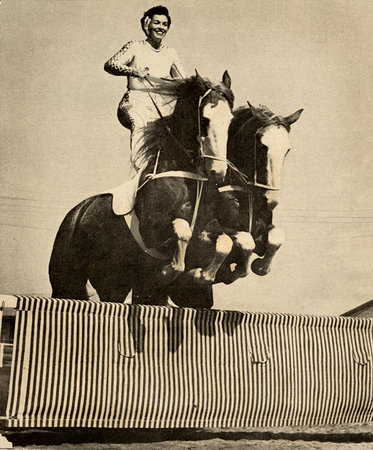 Pat Ommert and her steeds take a precision jump in preparation for the Roman Riding competition at the 1959 Flintridge Amateur Horse Show in La Cañada Flintridge.