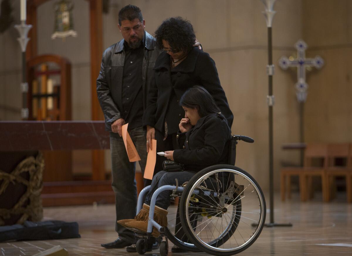 Gabriela Perez, 21, pauses with her parents Friday after an immigration vigil at the Cathedral of Our Lady of Angels. Perez, who was born in Mexico, came to the United States seeking treatment for spina bifida.