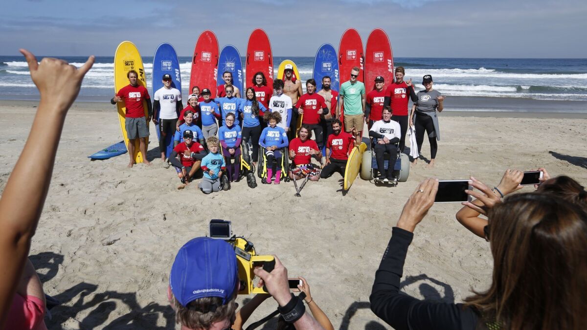 Participants and volunteers take a photo before heading out to the water during the Junior Seau Foundation Youth Adaptive Surfing Camp in Del Mar on Thursday.