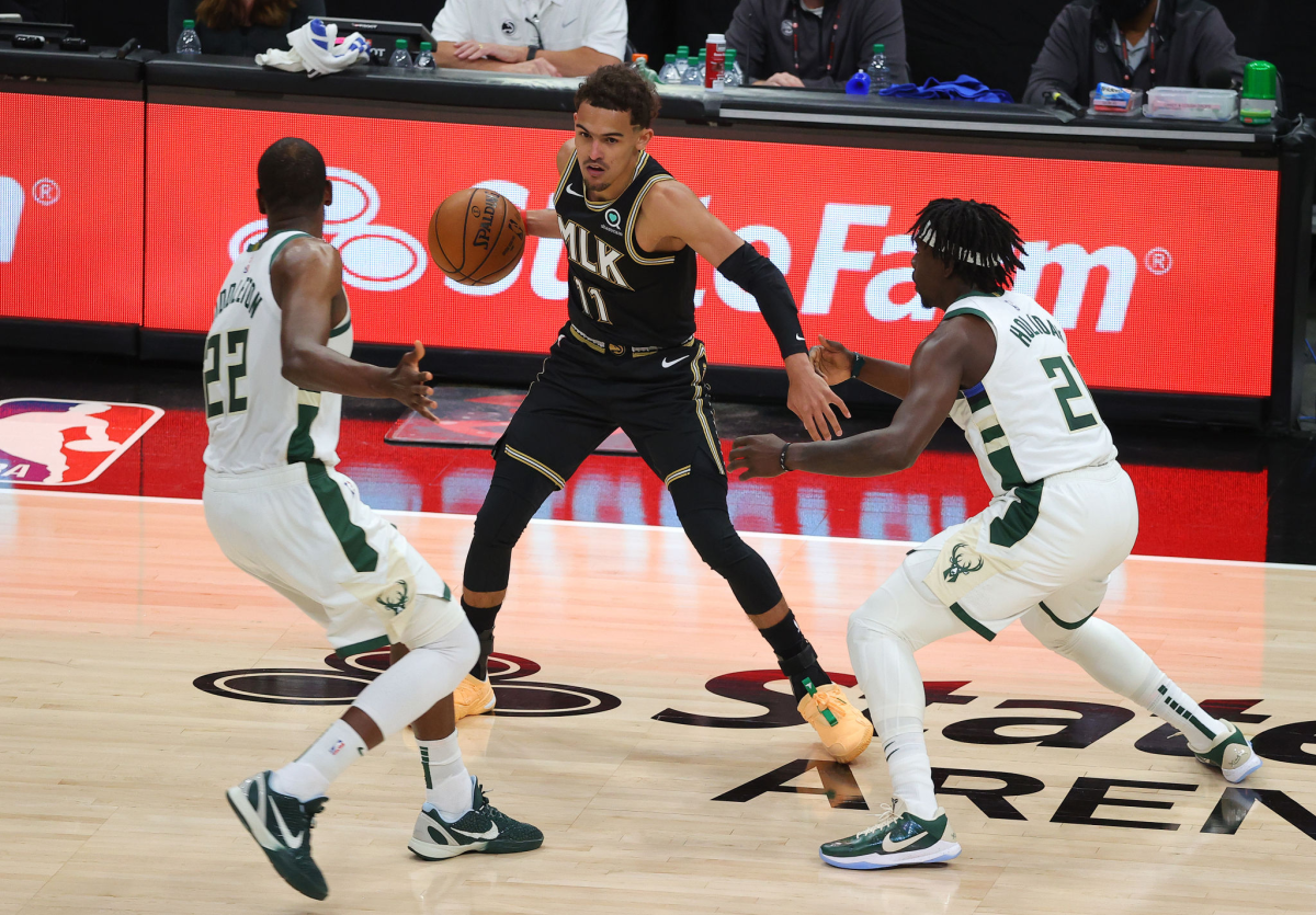 The Hawks' Trae Young is defended by the Bucks' Khris Middleton, left, and Jrue Holiday on July 3, 2021.