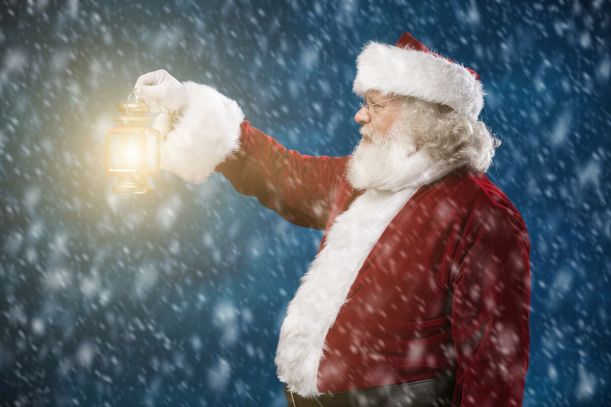 Santa holds a lantern in a snowstorm.