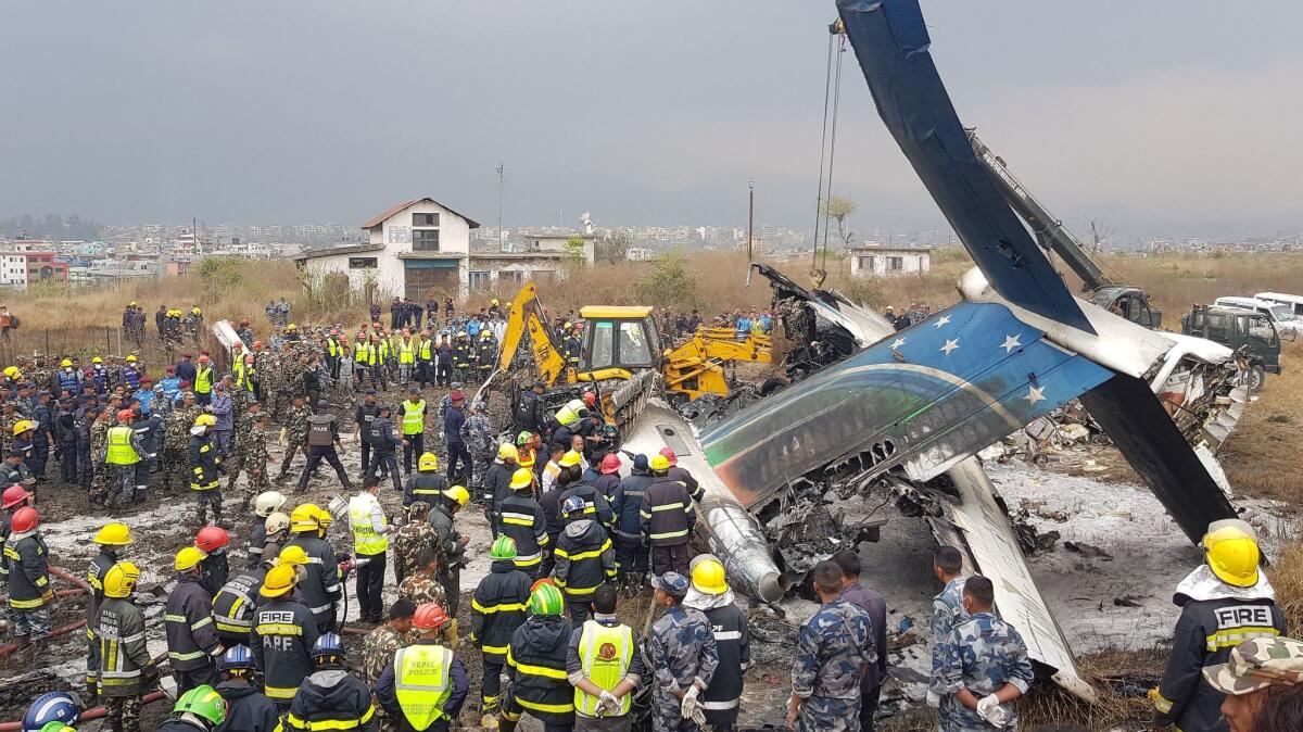 Rescue workers gather around the debris of an airplane that crashed near the international airport in Katmandu, Nepal, on March 12.