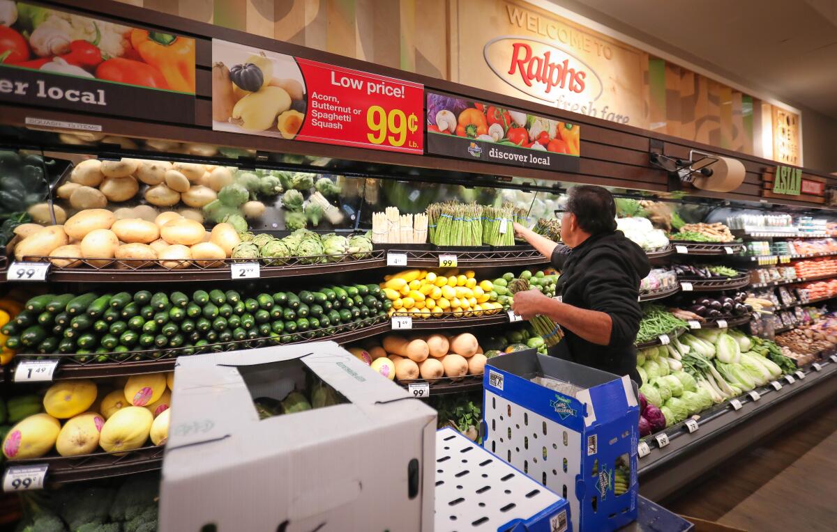 A clerk stocks produce at a market.