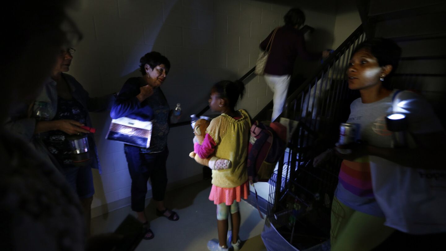 Evacuees use flashlights so others can maneuver around the stairway at Hampton Inn and Suites in Estero, Fla.